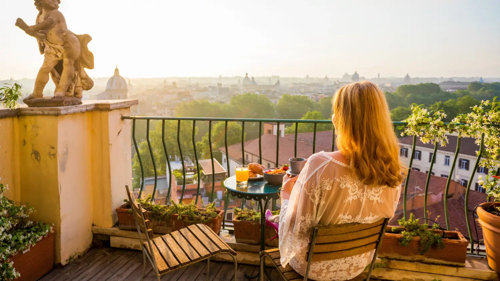 Woman taking breakfast while seated on sunny balcony