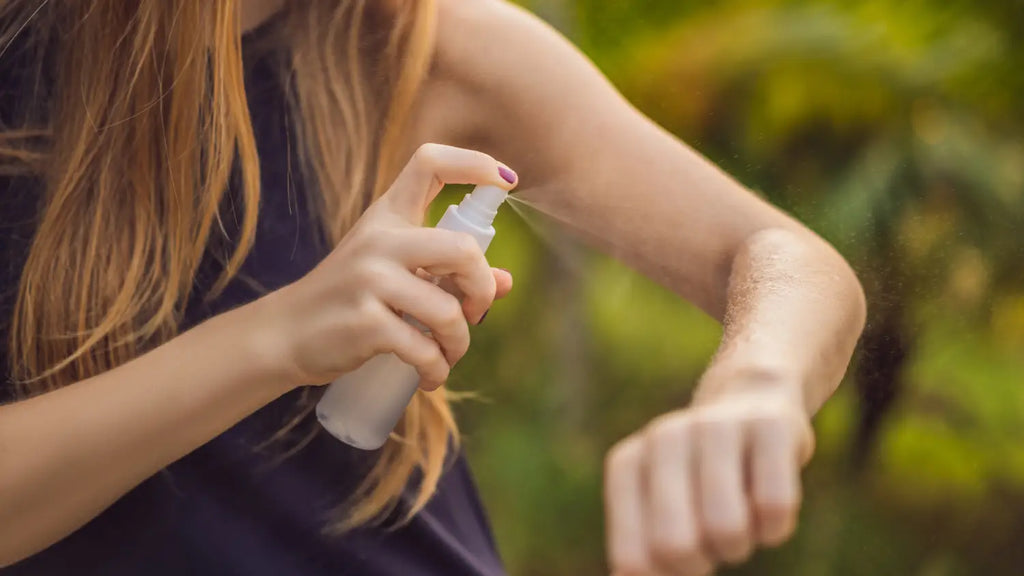 Woman spraying natural repellent on skin