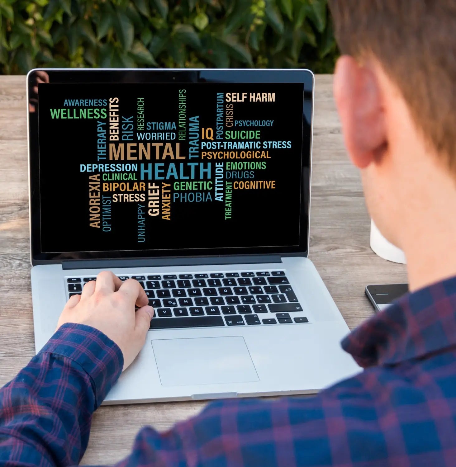 man looking at a computer screen where words related to mental health are displayed.