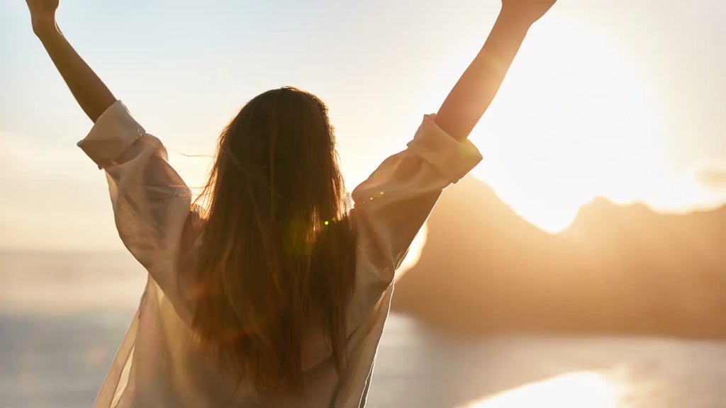 Woman with open arms during sunset