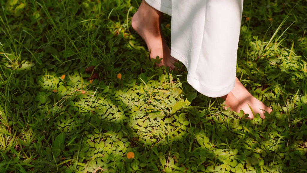 Woman walking barefoot on grass, grounding practice