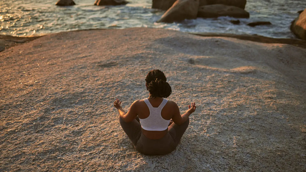Woman meditating at the beach during sunset