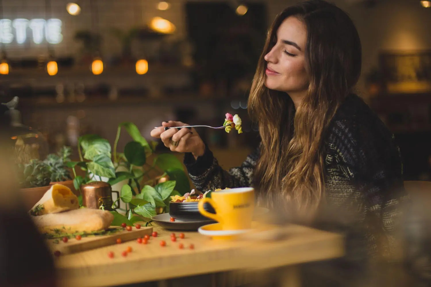 Woman eating a pasta meal and smiling.