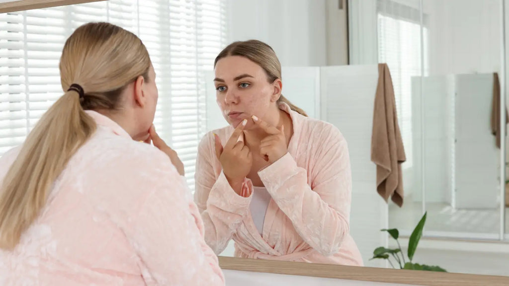 Woman looking at pimples on mirror