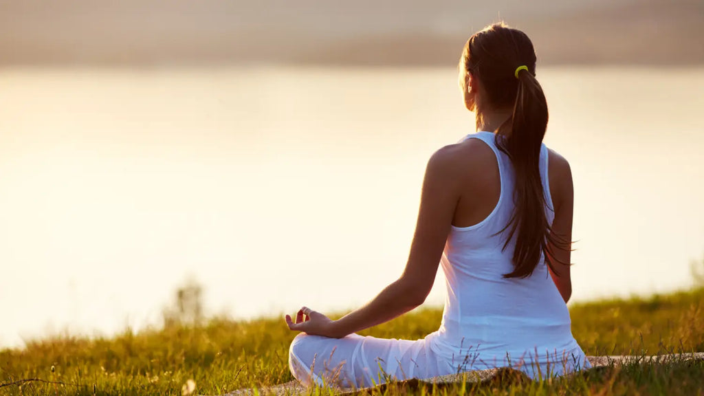 Woman meditating next to river