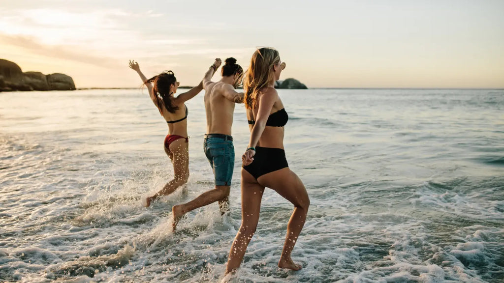 Group of friends walking in the beach towards the sea