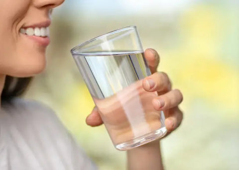 Woman holding a glass of water and smiling.