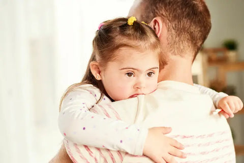 Man hugging a little girl with Down syndrome.