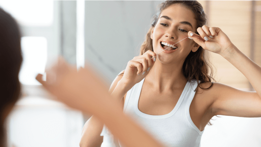 Woman flossing in front of mirror