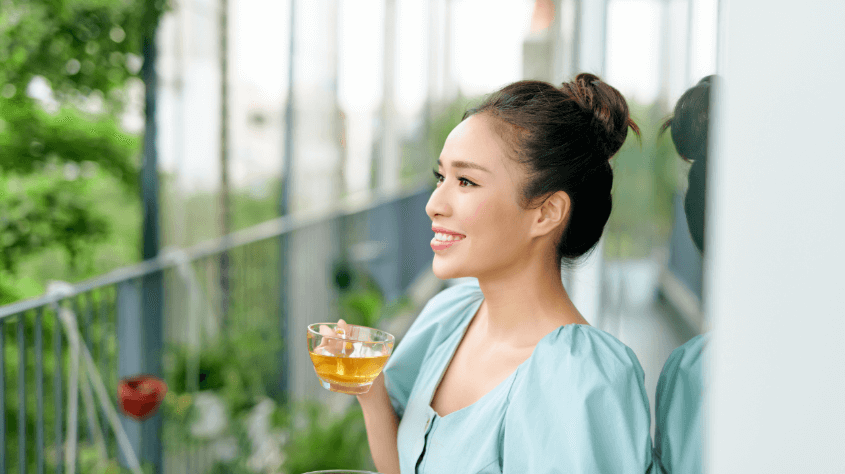 Woman drinking tea and smiling at landscape