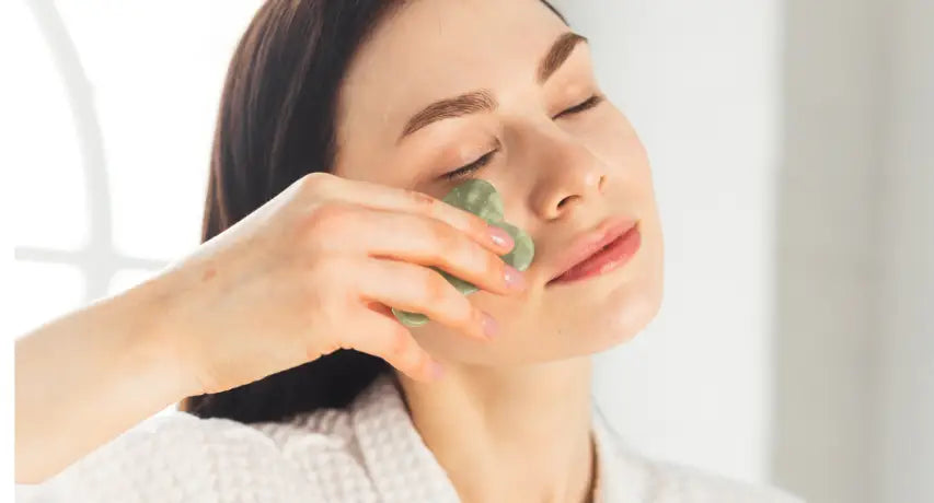 Woman massaging her face with gua sha tool