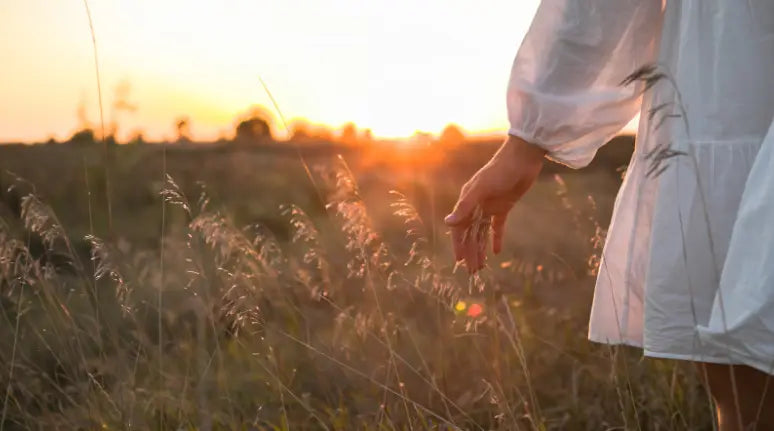 Woman spending time in nature, walking in field during sunset