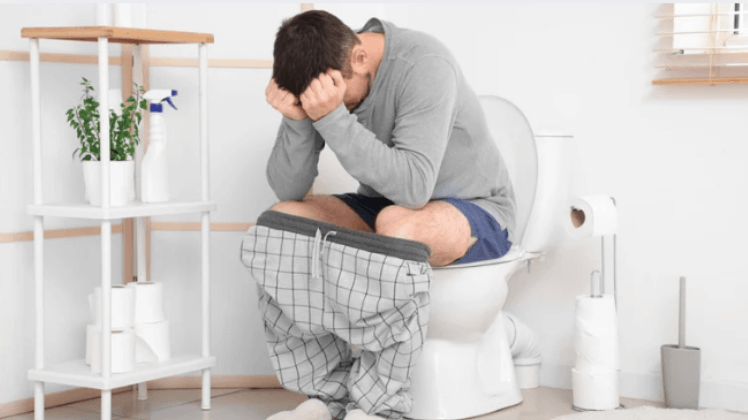 Man sitting on toilet suffering from hemorrhoids