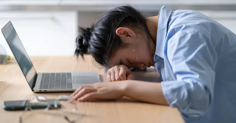 Woman feeling tired laying her head on desk
