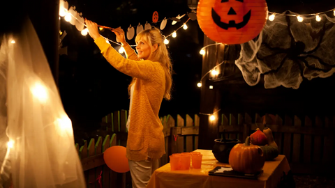 Woman putting up Halloween decorations on yard