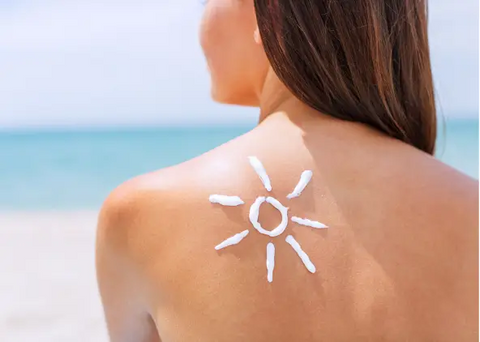 Woman tanning at the beach with sunscreen cream on her shoulder.