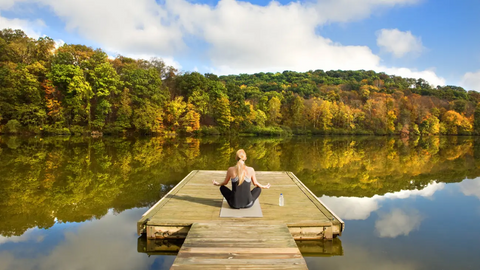 Woman meditating next to river