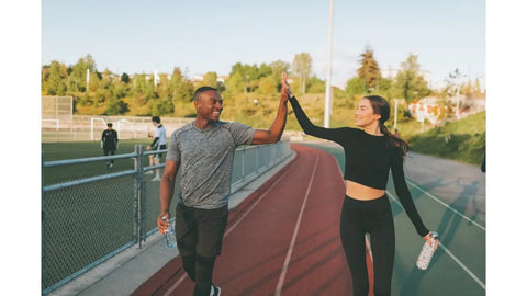 Couple exercising outdoors giving a high five.