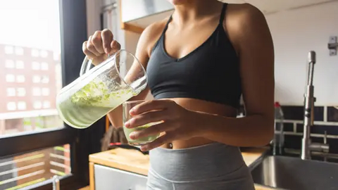 Woman pouring a green smoothie into a glass