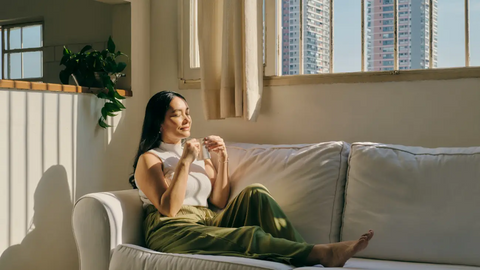 Woman sitting on couch enjoying the sun on her face