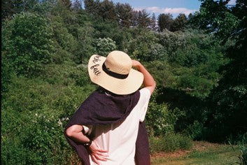 Woman protecting herself from the sun with a hat.