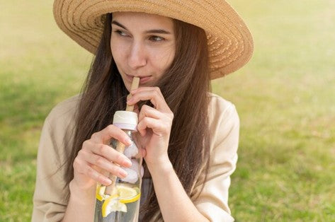 Woman drinking water outside.