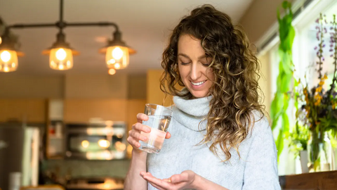 Woman taking supplements with water