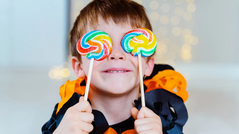 Kid holding two lollipops in front of his eyes