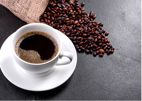 Cup of coffee alongside coffee grains