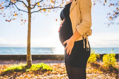 Pregnant woman touching her belly in a park