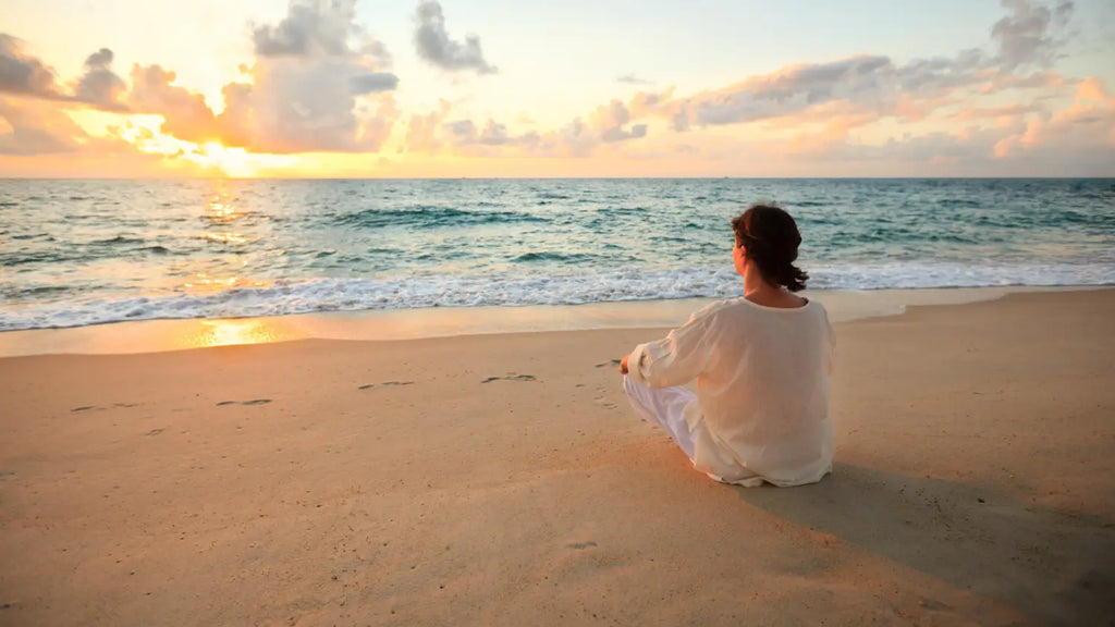 Woman sitting on the beach looking at the ocean
