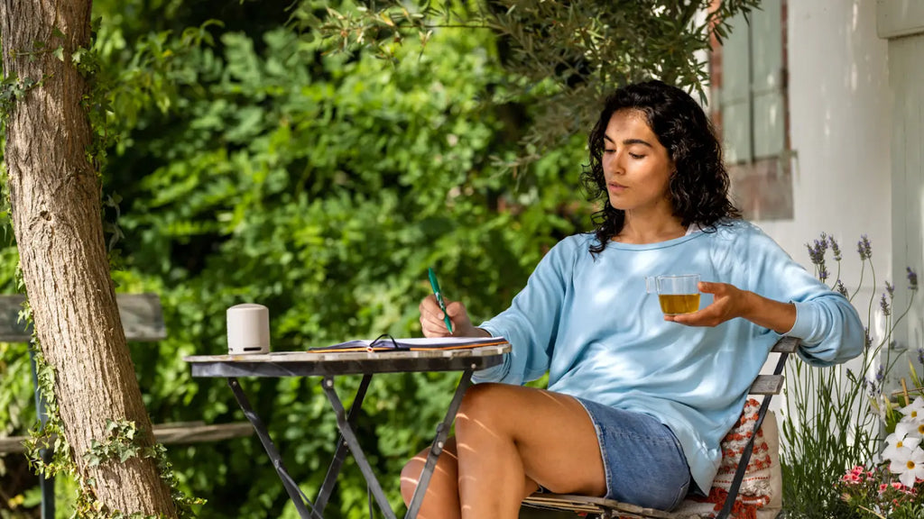 Woman journaling on patio surrounded by nature