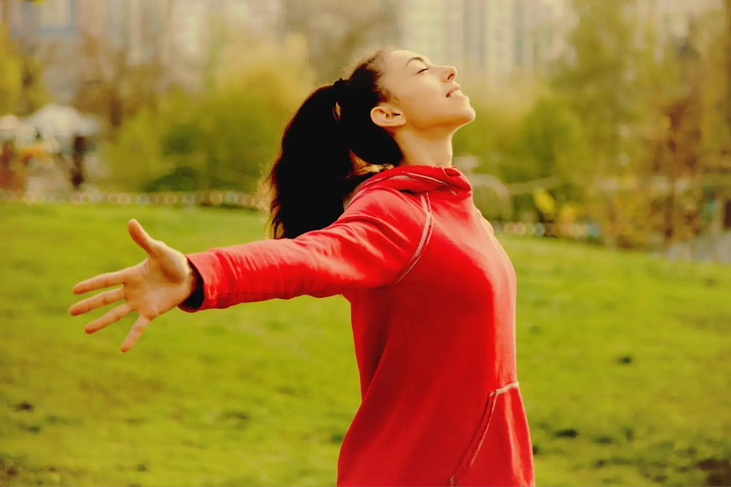 Woman with open arms and smiling in nature.